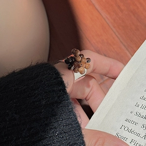 Close-up of S925 sterling silver ring with brown beads on hand against wooden desk
