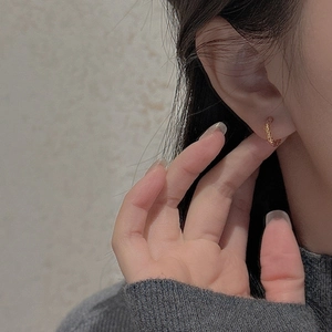 Elegant twisted rope texture hoop earring in gold finish worn by model on ear