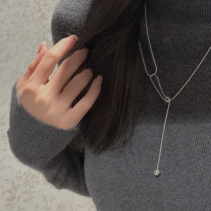 Macro detail of silver Y-shaped long necklace with polished bead pendant on model
