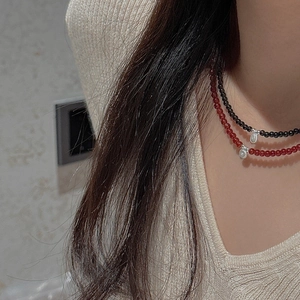 Close-up of S925 sterling silver beaded necklaces in black and red on a model's neck
