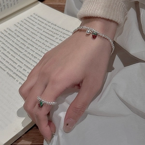 Set bracciale e anello in argento S925 con ciondolo a fragola su sfondo di libro d'epoca