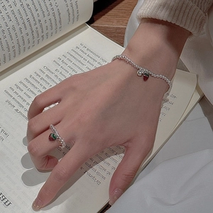 Set bracciale e anello con fragola in argento S925 su sfondo di un libro vintage