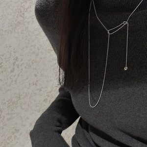 Close-up of minimalist S925 sterling silver lariat necklace on a grey sweater