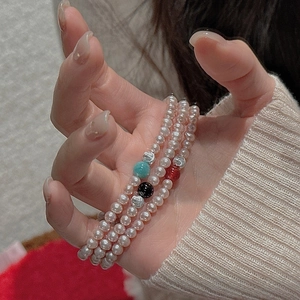 Detailed view of three-color beaded pearl bracelets with green, black, and red accents