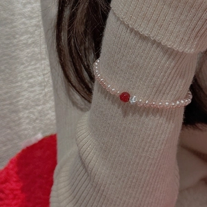 Detail of S925 sterling silver beaded bracelet with central red bead on model's wrist