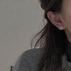Close-up of minimalist S925 silver pearl earring worn by model on grey background