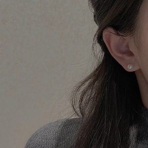 Detailed view of 6mm sterling silver pearl earrings worn by a model in a minimal setting