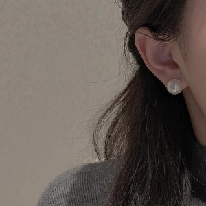Close-up of a minimalist S925 silver stud earring with a white pearl on a model's ear
