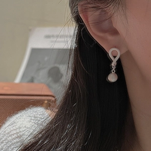 Close-up of S925 silver knot earrings with hanging white pearl on model ear