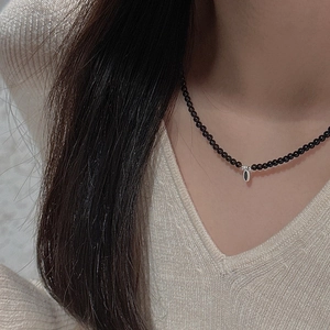 Close-up of minimalist black beaded S925 silver necklace with oval pendant on neck