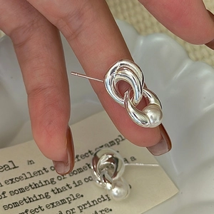 Boucles d'oreilles perles en argent S925 avec anneaux imbriqués tenues à la main