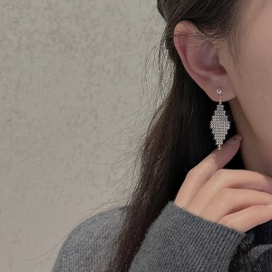 Detailed macro view of S925 sterling silver diamond mesh tassel earrings on model