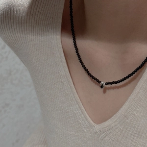 Detail of S925 sterling silver beaded necklace with black waterdrop pendant on model