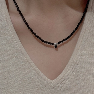 Elegant S925 silver beaded necklace with black teardrop pendant on a beige knit sweater