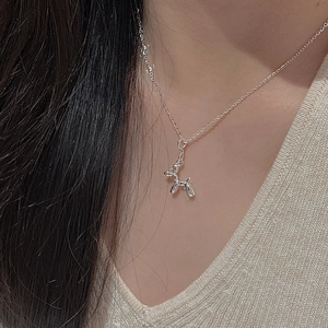 Close-up of S925 sterling silver balloon dog pendant necklace worn on a V-neck sweater