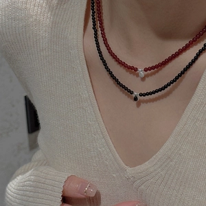 Detail of layered S925 silver beaded necklaces with red and black teardrop pendants