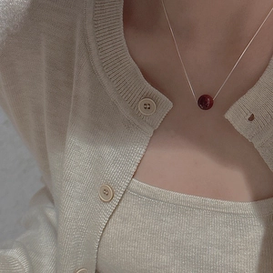 Detailed view of a minimalist S925 silver necklace featuring a deep red round bead pendant