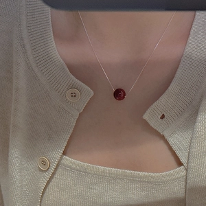 Detail of S925 sterling silver necklace with a red bead pendant worn on the neck
