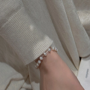 Close-up of minimalist S925 silver pearl bracelet on wrist with a soft knit background