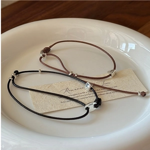 Détail des fermoirs en argent S925 et des cordons en cuir tressé sur bracelets minimalistes