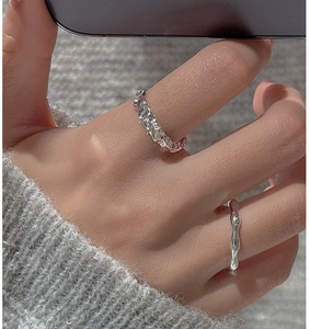 Detail of S925 sterling silver rings featuring hammered texture and wave design on finger