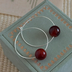Minimalist S925 sterling silver hoop earrings with dark red beads on a jewelry box