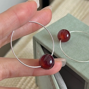 S925 sterling silver hoop earrings with a round red agate bead on a jewelry box