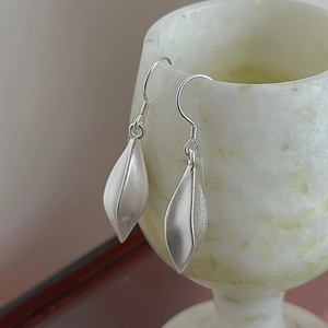 S925 sterling silver leaf earrings with matte finish on elegant white marble cup