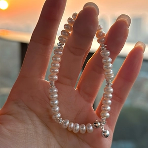 Minimalistisches S925 Silber Süßwasserperlen-Armband mit Glockenanhänger in der Hand