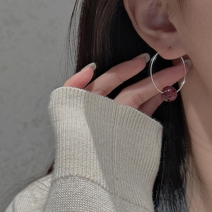Detail of a minimalist S925 silver hoop earring with a vintage purple bead on a model