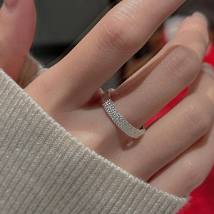 Detail of S925 sterling silver ring with textured finish on finger in warm indoor light