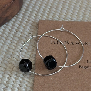S925 sterling silver hoop earrings with black natural stone bead on card background