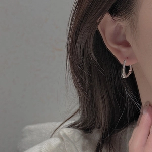 Close-up of S925 sterling silver bamboo-shaped hoop earrings worn on a model's ear