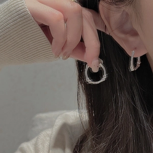 Close-up of S925 sterling silver bamboo hoop earrings on a model wearing a soft sweater