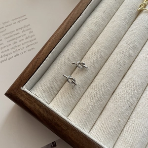Minimalist S925 sterling silver knot stud earrings displayed in a beige jewelry box