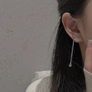 Detail of silver long tassel earrings featuring an eye design with dangling metal droplets