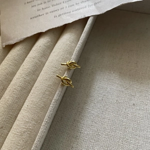 Minimalist S925 sterling silver gold knot stud earrings on a textured background