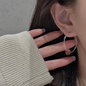 Close-up of S925 sterling silver hoop earring with vintage amber red bead on ear