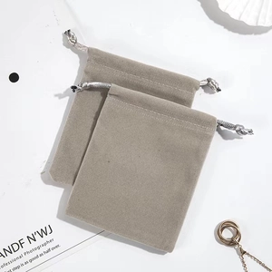 Lot de deux pochettes à bijoux en velours gris avec cordons sur fond élégant et épuré