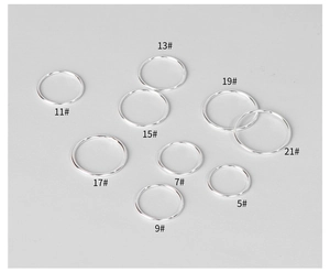 Nove anelli sottili in argento stile minimalista in misure da 5 a 21 su sfondo grigio