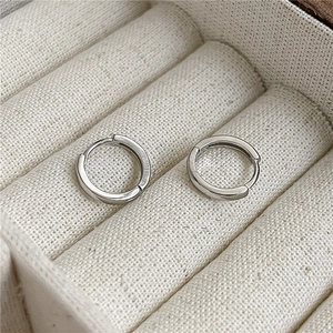 Créoles minimalistes en argent sterling S925 présentées sur un plateau à bijoux en velours beige