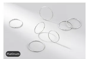 Close-up of 7 minimalist S925 sterling silver textured stacking rings in white gold