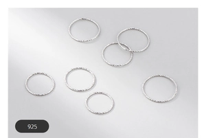 Detailed macro view of seven S925 sterling silver minimalist rings with textured patterns