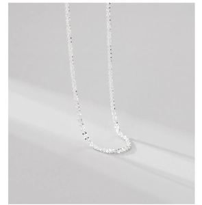 Macro detail of shimmering S925 sterling silver chain with sparkle finish and soft shadows