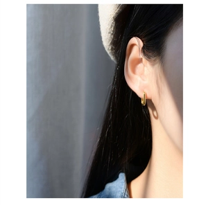 Close-up of minimalist gold-plated U-shaped earrings worn by a model in casual style