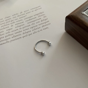 Macro detail of a minimalist silver horseshoe open ring on a vintage book background