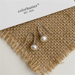 Boucles d'oreilles élégantes en perles blanches sur toile de jute avec crochets argentés