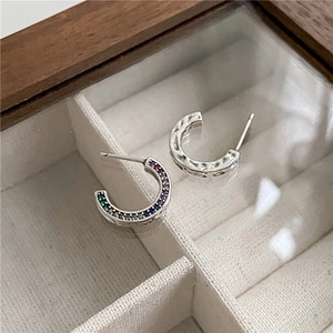 Détail de boucles d'oreilles C en argent avec zircons arc-en-ciel et texture martelée main