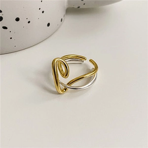 Vue macro des fils dorés et argentés entrelacés sur une bague ouverte minimaliste