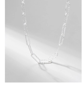 Macro detail of S925 sterling silver chain with hammered texture and geometric shadows